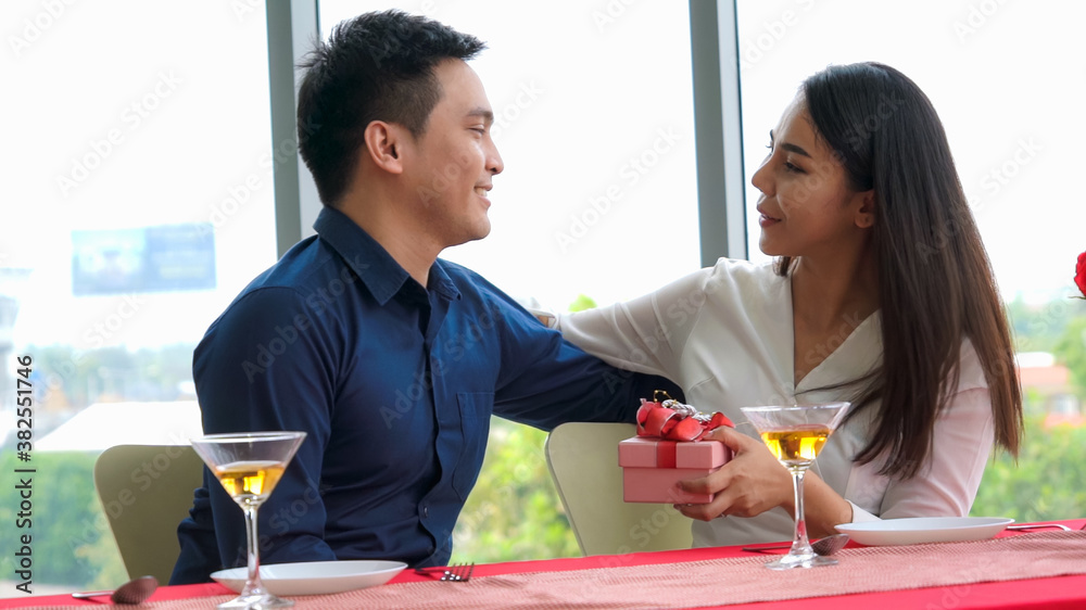 Romantic couple giving gift to lover at restaurant . Happy couple lifestyle .