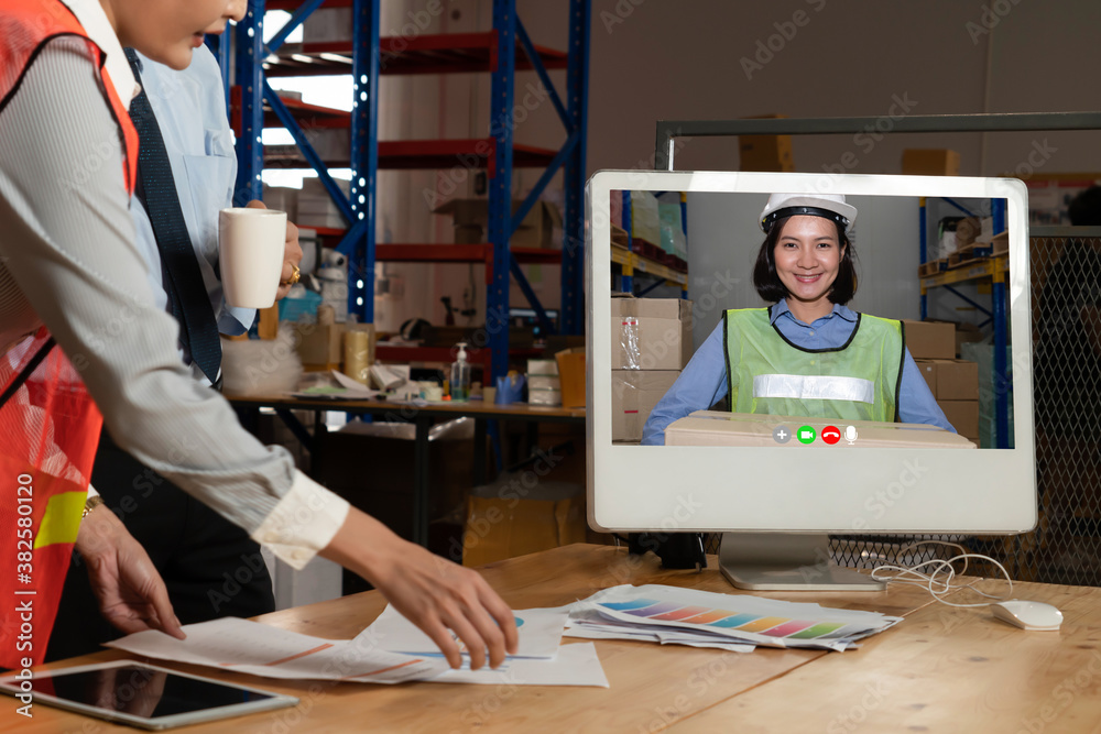 Warehouse staff talking on video call at computer screen in storage warehouse . Online software tech