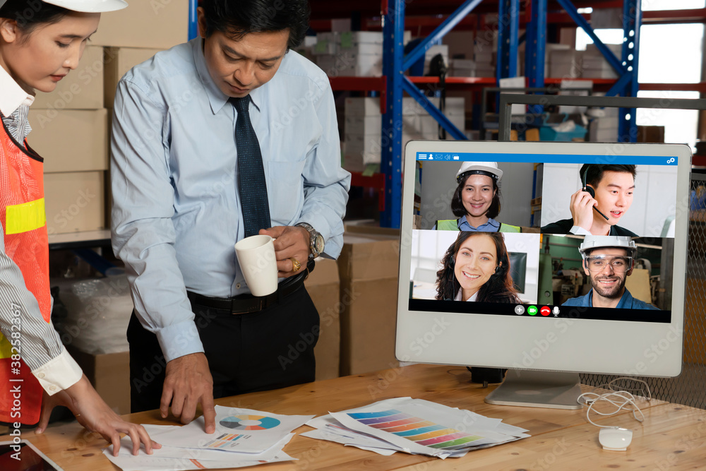 Warehouse staff talking on video call at computer screen in storage warehouse . Online software tech