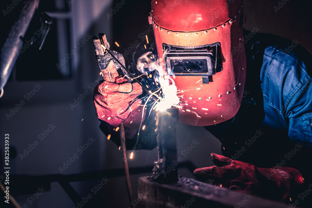 Metal welding steel works using electric arc welding machine to weld steel at factory. Metalwork man