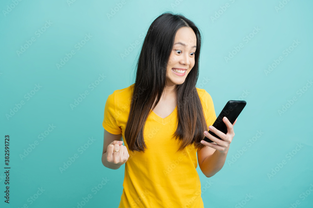 Beautiful Asian woman. She feels shocked with the phone on a yellow background.