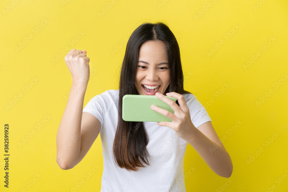 Beautiful Asian woman. She feels shocked with the phone on a yellow background.