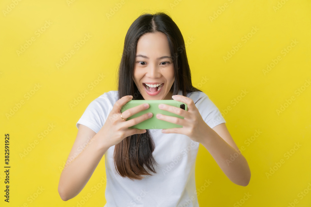 Beautiful Asian woman. She feels shocked with the phone on a yellow background.