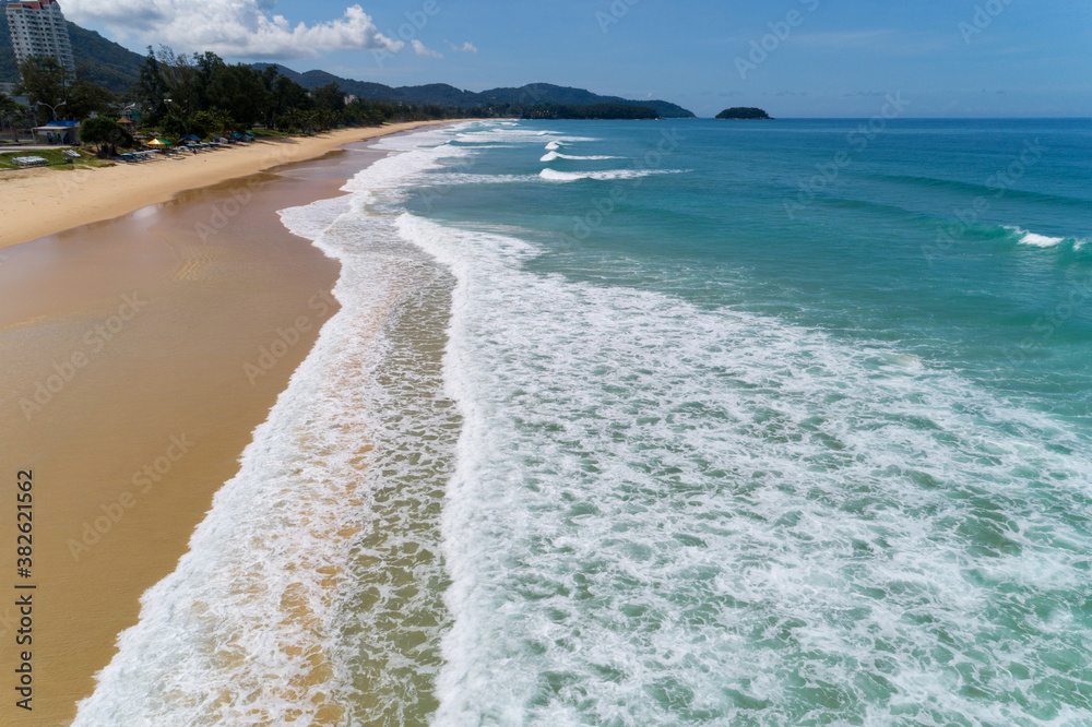 Beautiful wave crashing on sandy shore at karon beach in phuket thailand,aerial view drone shot.