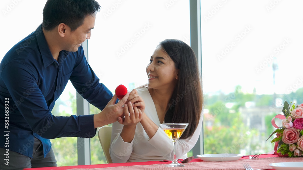 Romantic couple giving gift to lover at restaurant . Happy couple lifestyle .