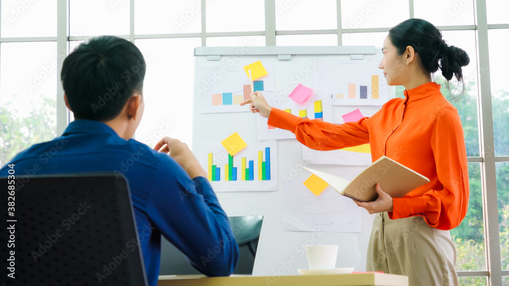 Young woman explains business data on white board in casual office room . The confident Asian busine