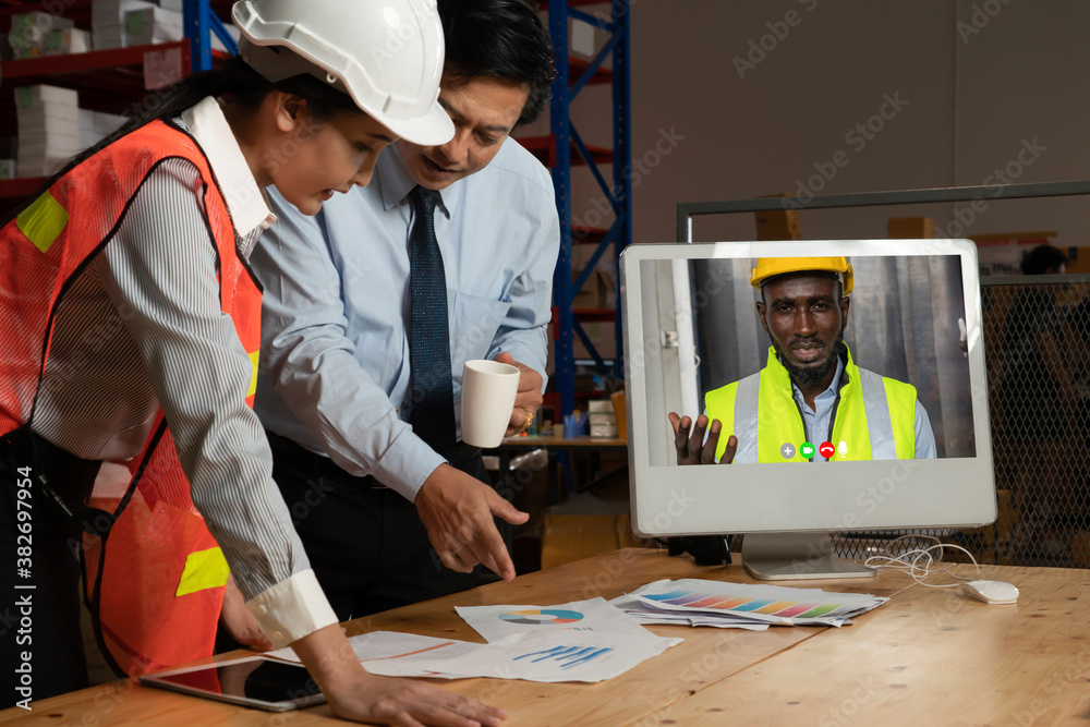 Warehouse staff talking on video call at computer screen in storage warehouse . Online software tech