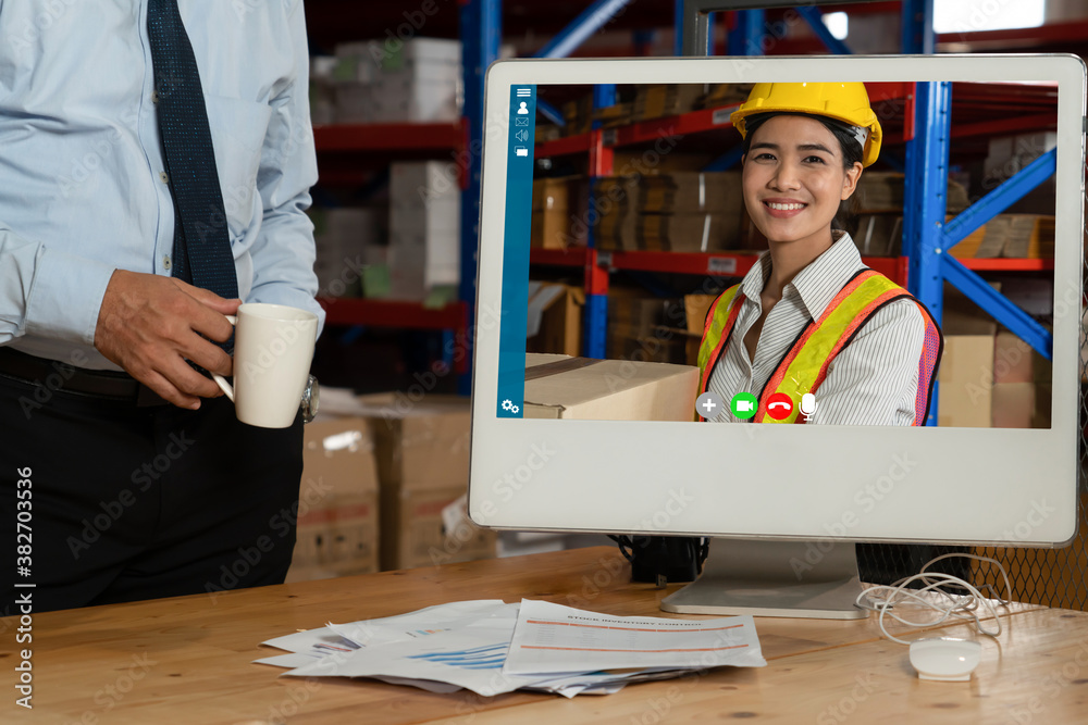 Warehouse staff talking on video call at computer screen in storage warehouse . Online software tech