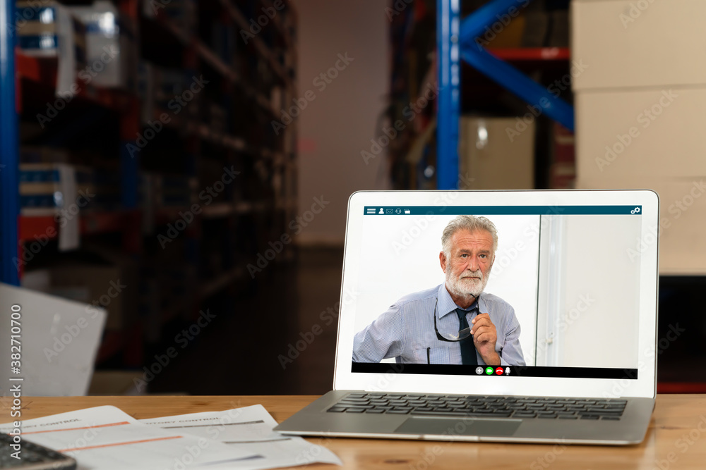 Warehouse staff talking on video call at computer screen in storage warehouse . Online software tech