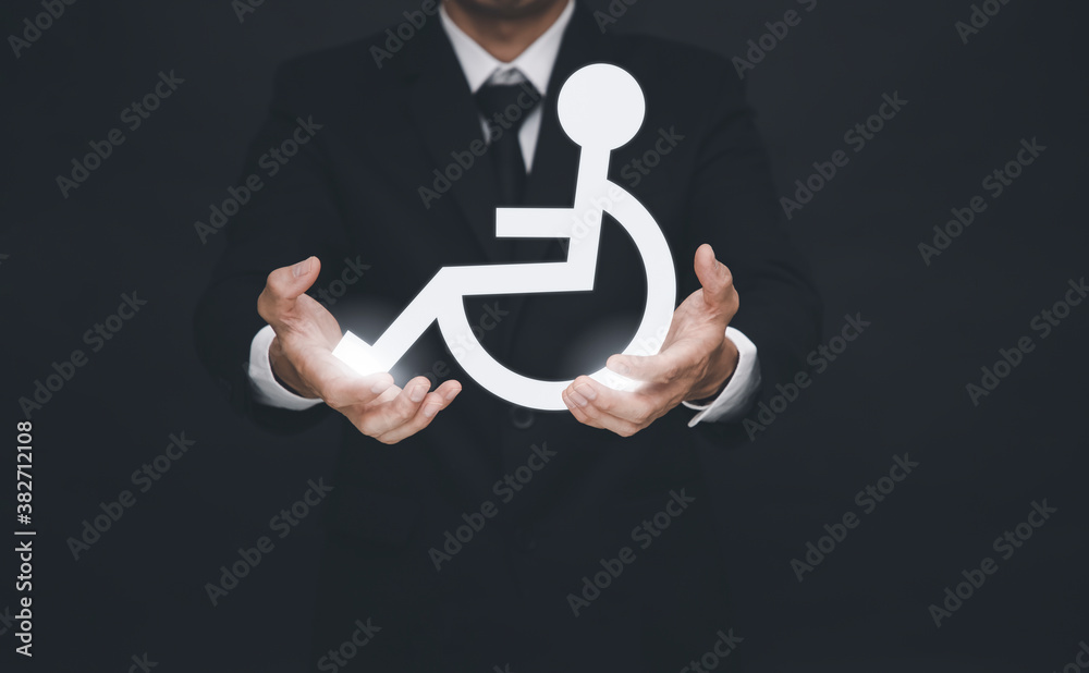 Businessman holding a white wheelchair icon on the black background,Helping the disabled,Disabled pe