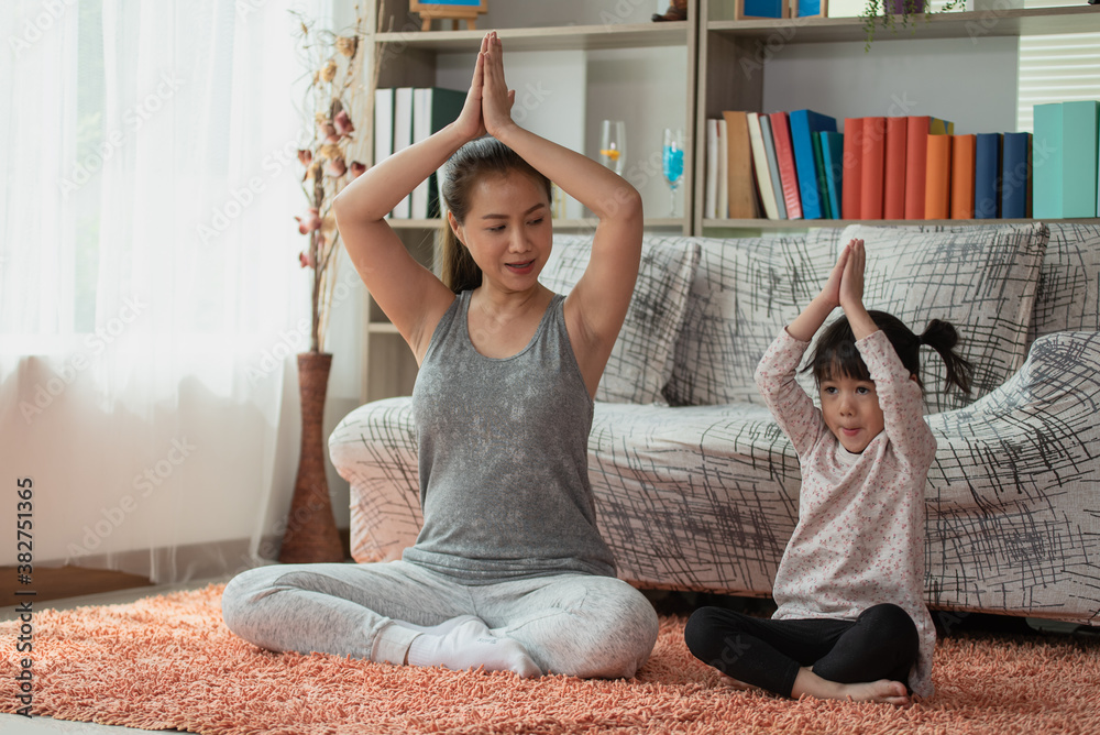 Mother and daughter doing yoga exercises together, Happy Asian family loving concept