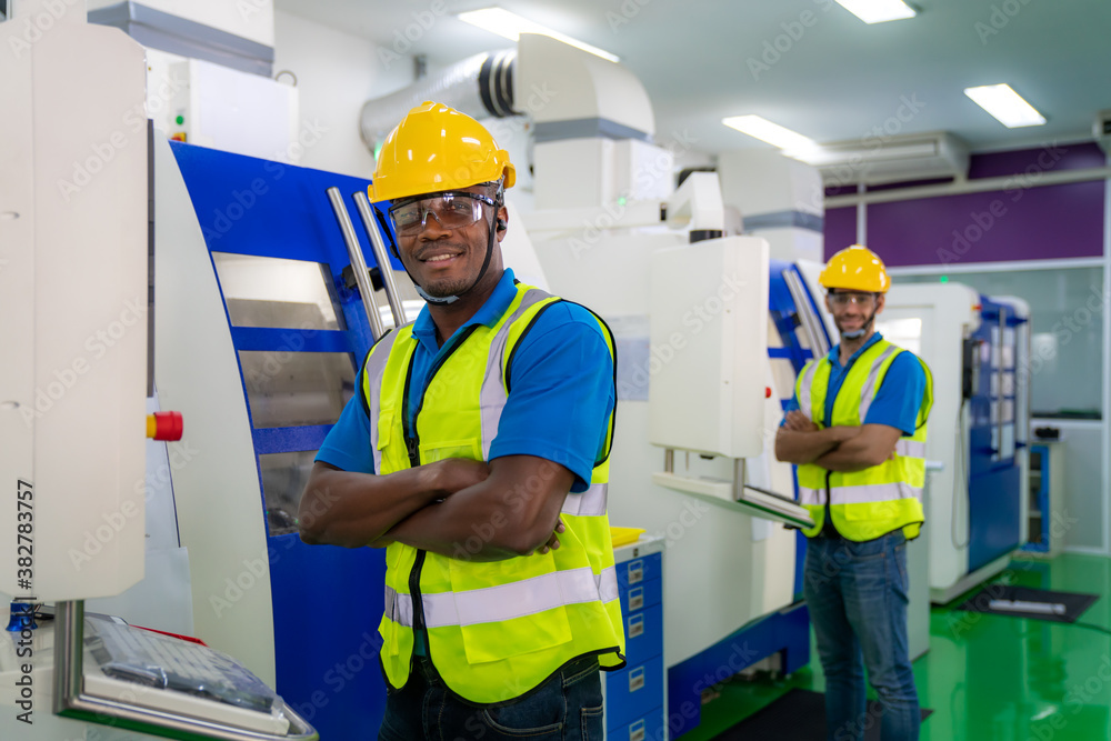 Two mechanical technician operative arm crossed in front of cnc milling cutting machine at factory a