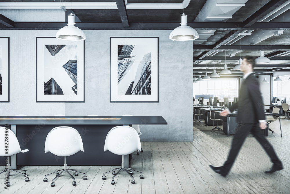 Businessman walking in office interior with  picture on wall.