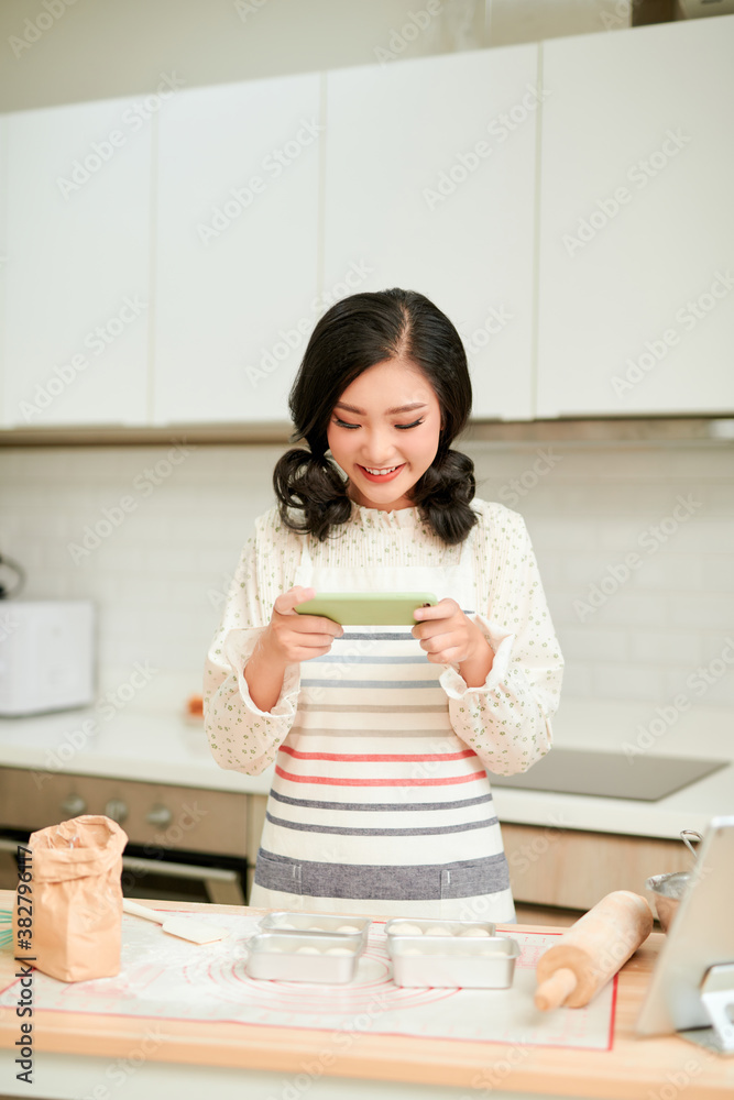 漂亮女人在烤盘上用新鲜的生蛋糕面糊拍照，女人的手涂着面粉