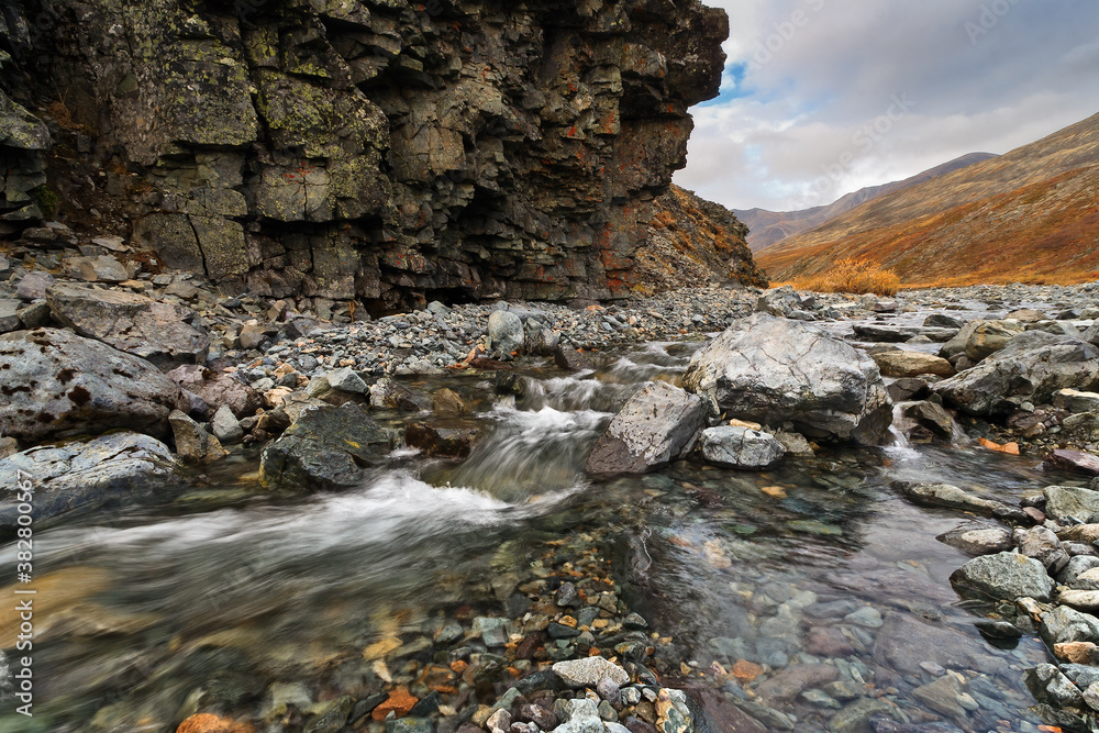 Autumn arctic landscape. A stream in a mountain gorge among the rocks. The nature of Chukotka and po