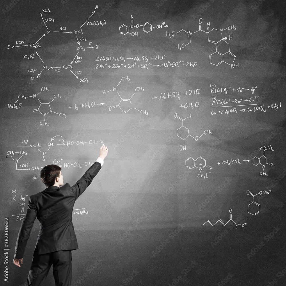 Scientist writing formulas on chalkboard