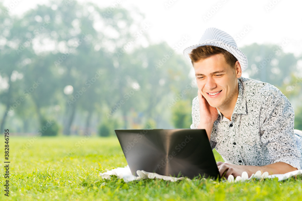 young man working in the park with a laptop