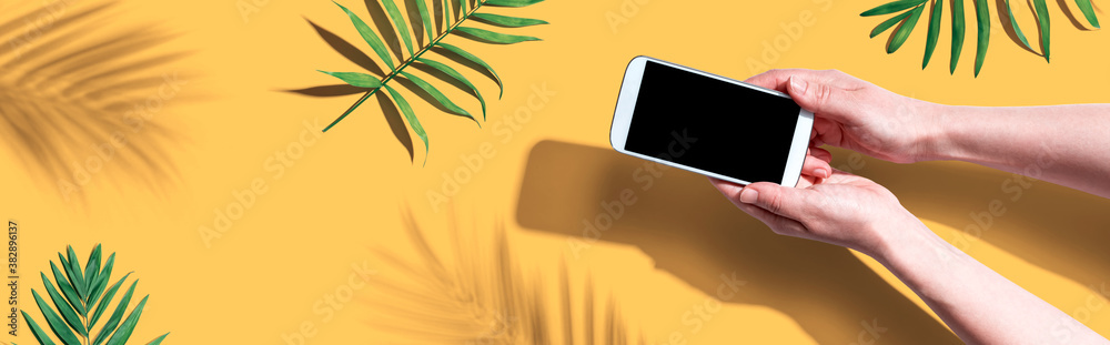 Smartphone with tropical palm leaves and shadow - flat lay