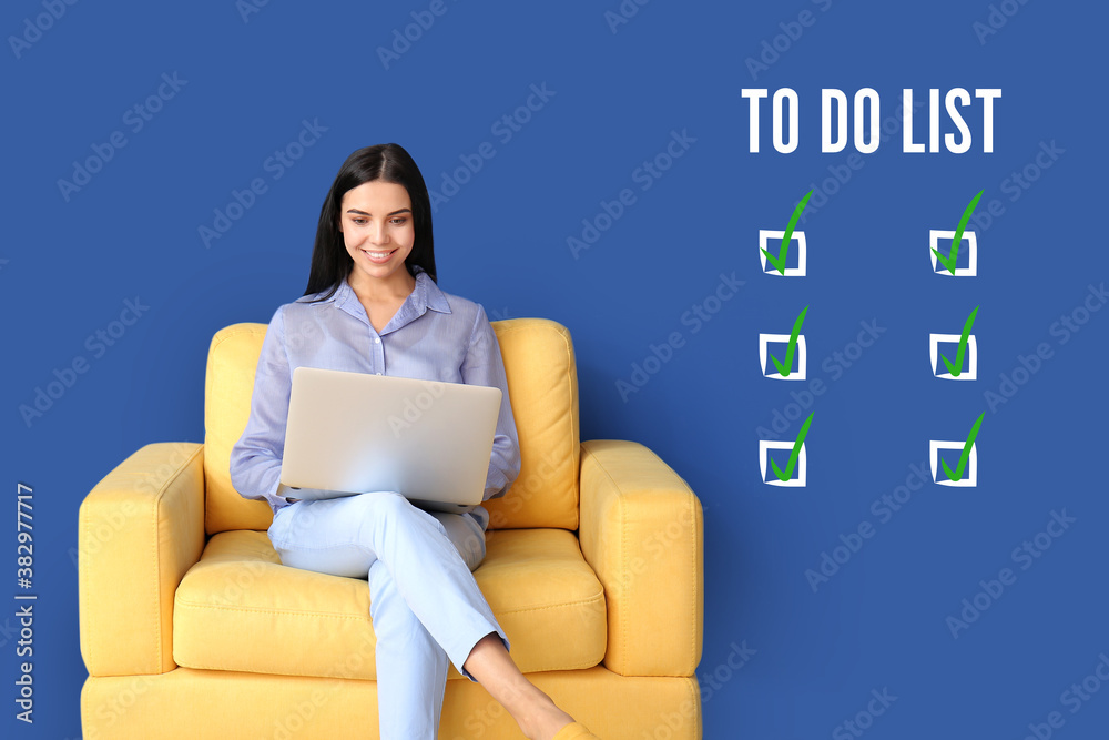 Young woman with laptop making to do list at home