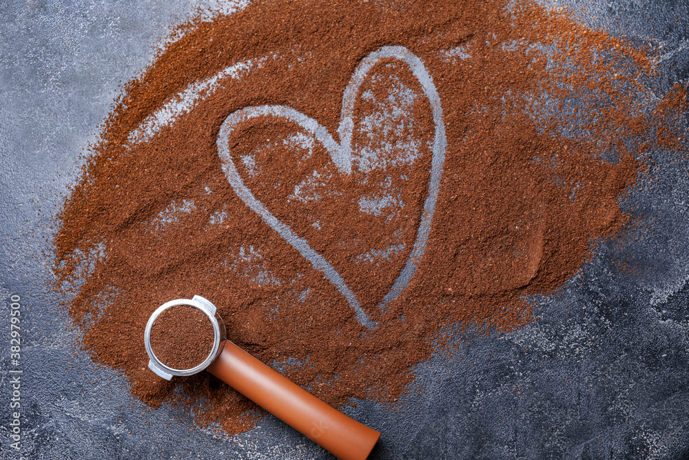 Portafilter with coffee powder and drawn heart on dark background