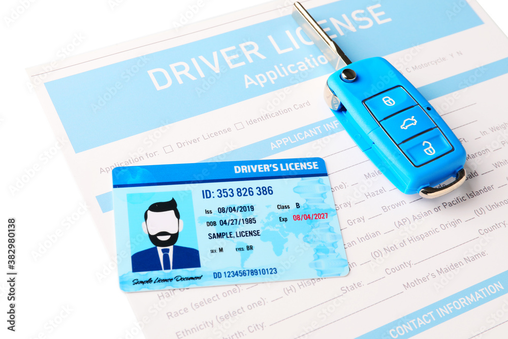 Driving license with application form and car key on white background, closeup