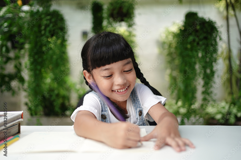 Asian student child girl writing on the paper book. Asian genius student doing a homework. education