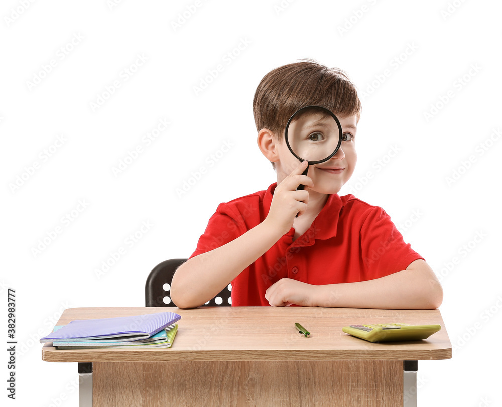 Little pupil sitting at school desk against white background