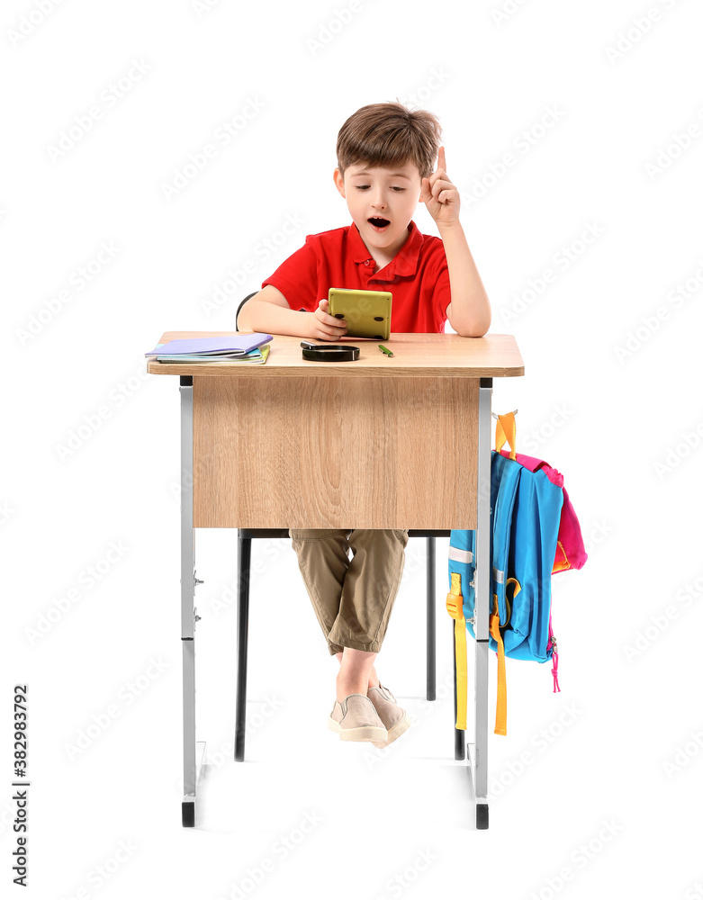 Little pupil with calculator sitting at school desk against white background