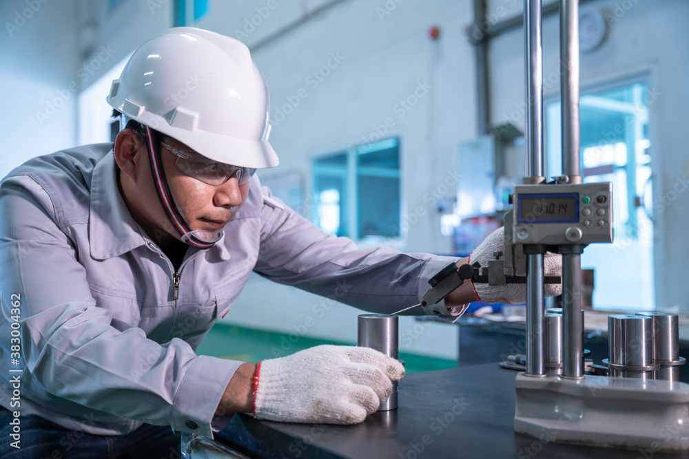 Asian technician worker wearing a safety suit and Quality Checking with hight gauge mass Product on 