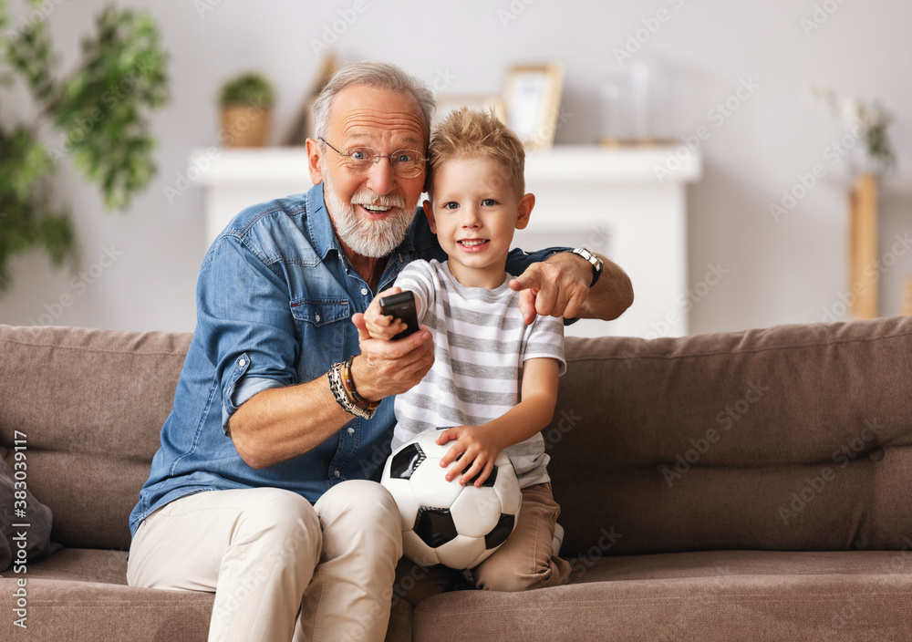 Cheerful grandfather and grandson watching football match.