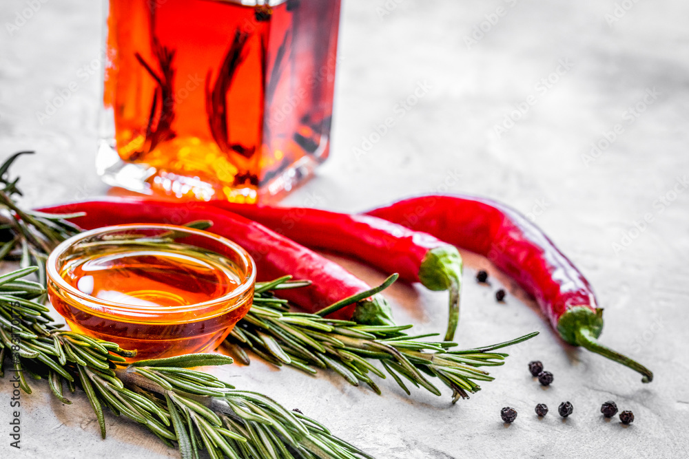 oil in carafe with spices and chili on stone background