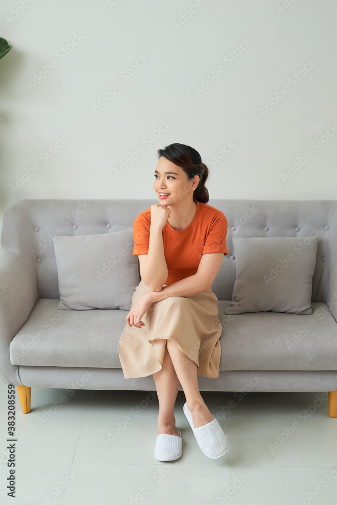 Young woman sitting on a sofa and looking in the camera on white background