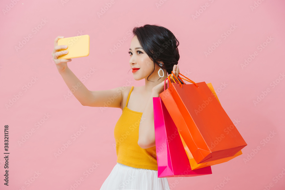 Attractive young woman wearing summer outfit standing isolated over pink background, taking a selfie