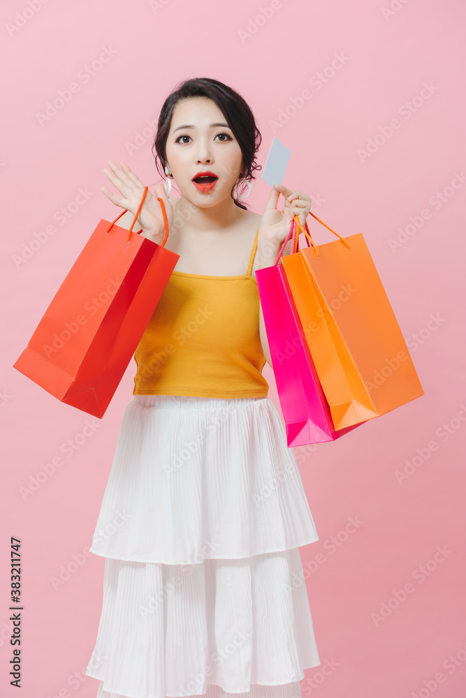 Beautiful young girl wearing casual clothes standing isolated over pink background, carrying shoppin