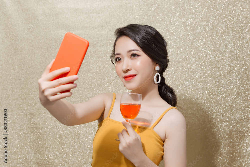 Young woman celebrating on party, drinking champagne in glass, smiling, taking selfie photo on smart