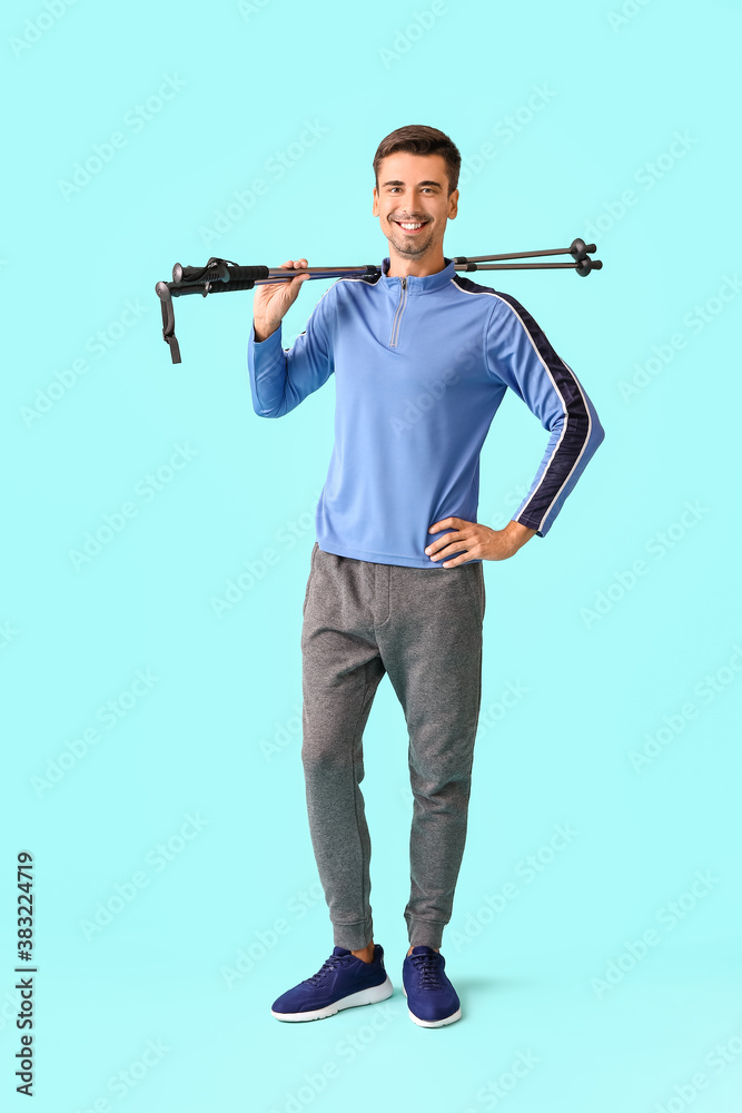 Young man with walking poles on color background