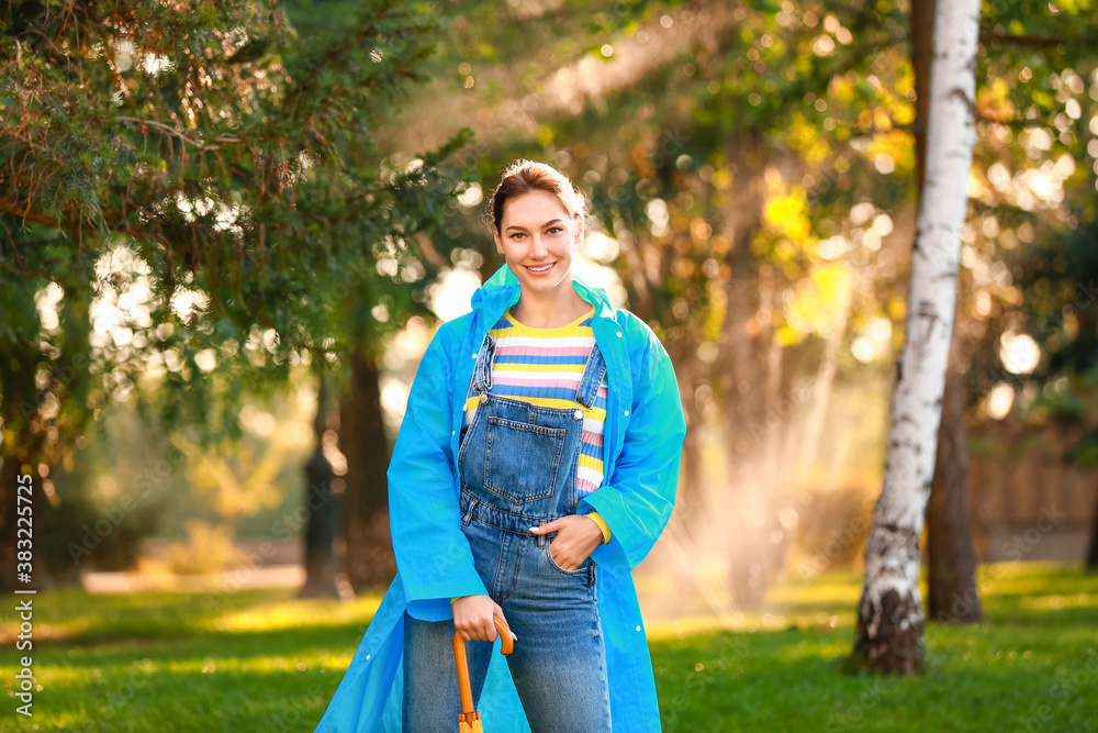 Beautiful young woman wearing raincoat in park