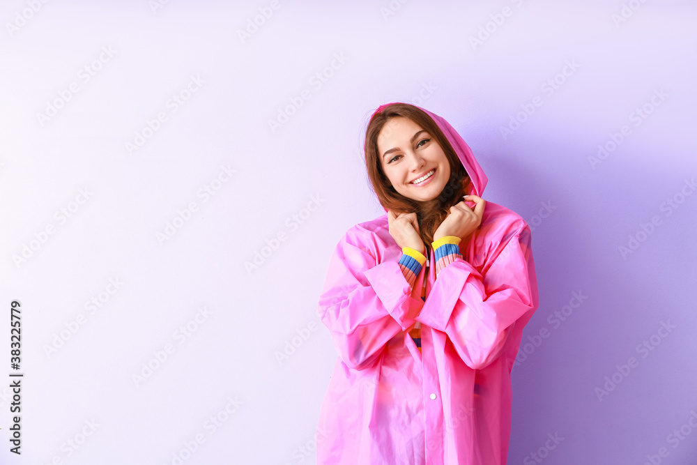 Beautiful young woman in raincoat on color background