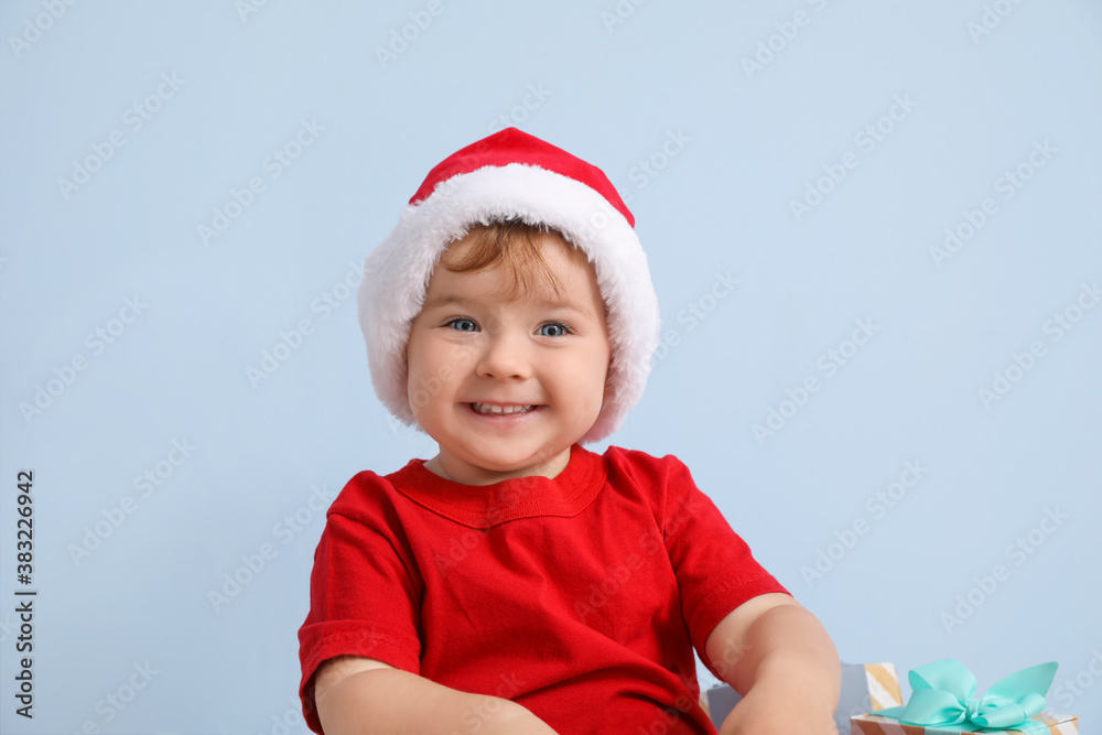 Cute little baby in Santa hat on color background