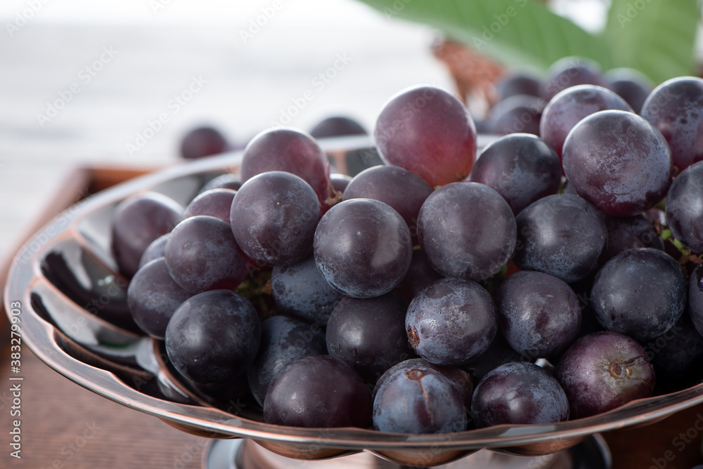 Delicious bunch of grapes fruit on a plate over wooden table background.