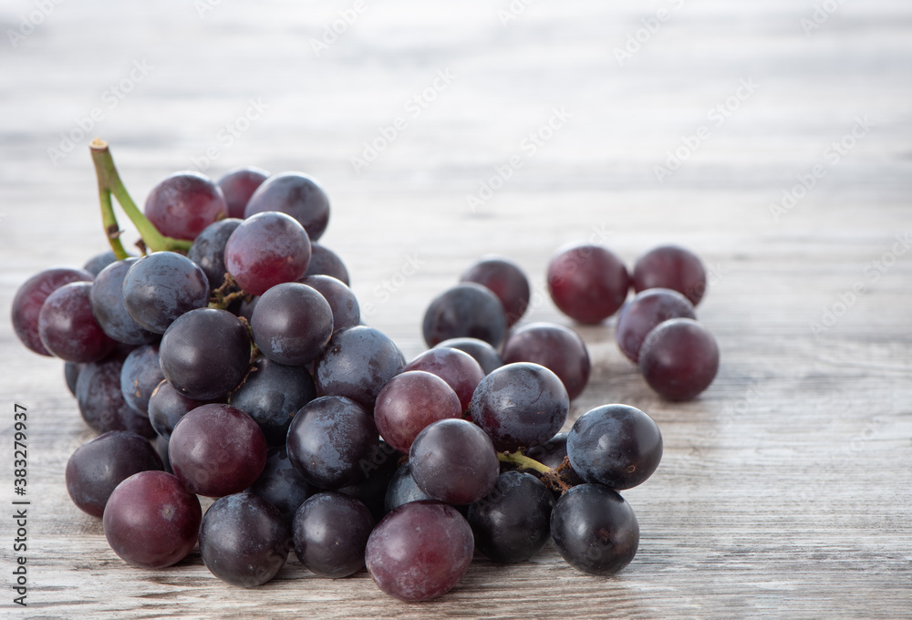 Delicious bunch of grapes fruit on a plate over wooden table background.