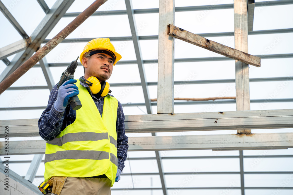 Construction worker using electric drill on house build.