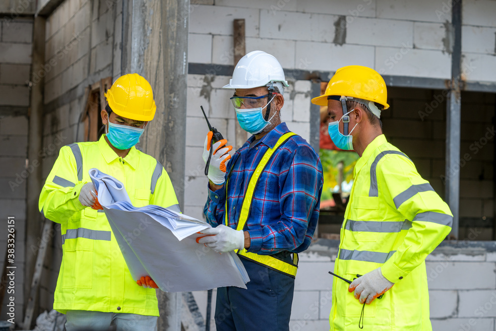 Team of engineer discussing project details with blueprints at construction site.