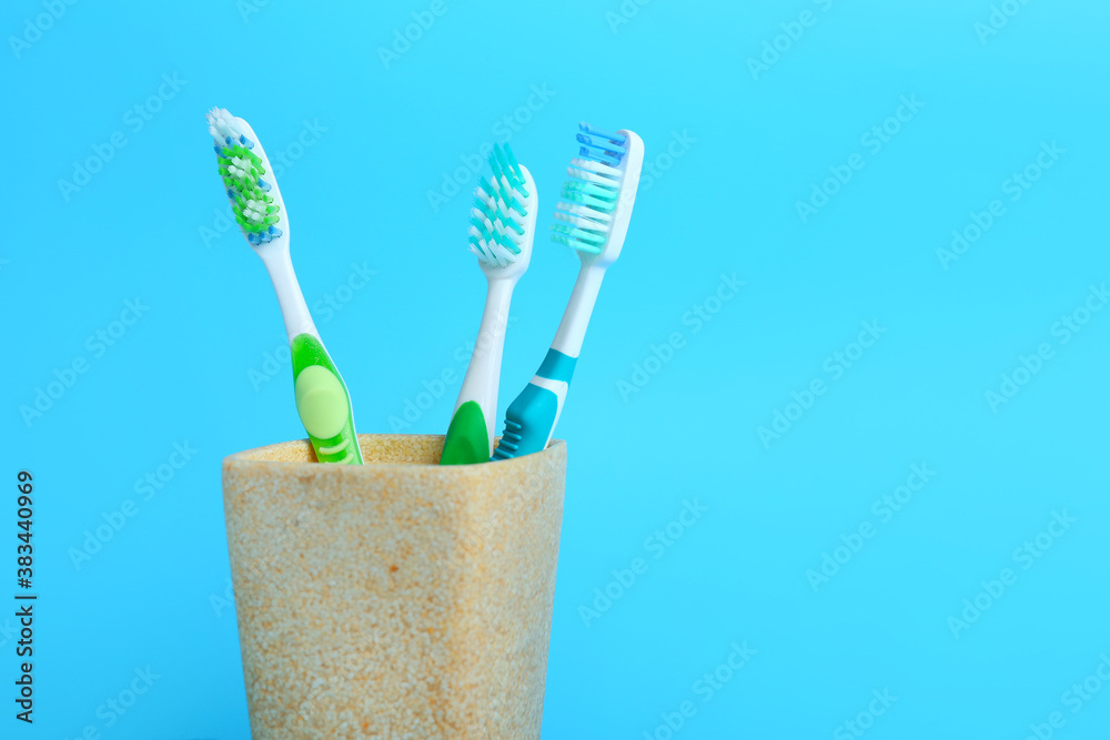 Cup with tooth brushes on color background