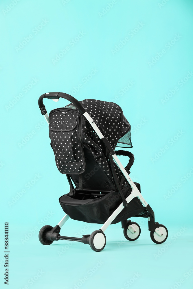 Modern baby stroller on color background