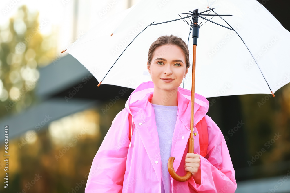 美丽的年轻女子，带着雨伞，在户外穿着雨衣