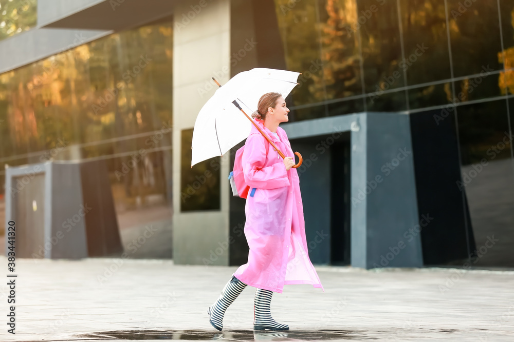 Beautiful young woman with umbrella wearing raincoat outdoors