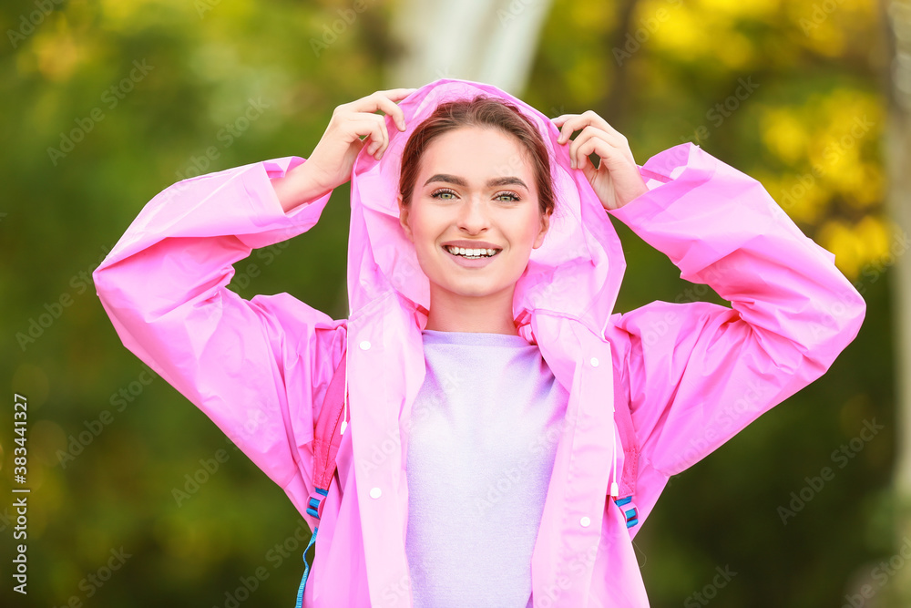 Beautiful young woman wearing raincoat outdoors