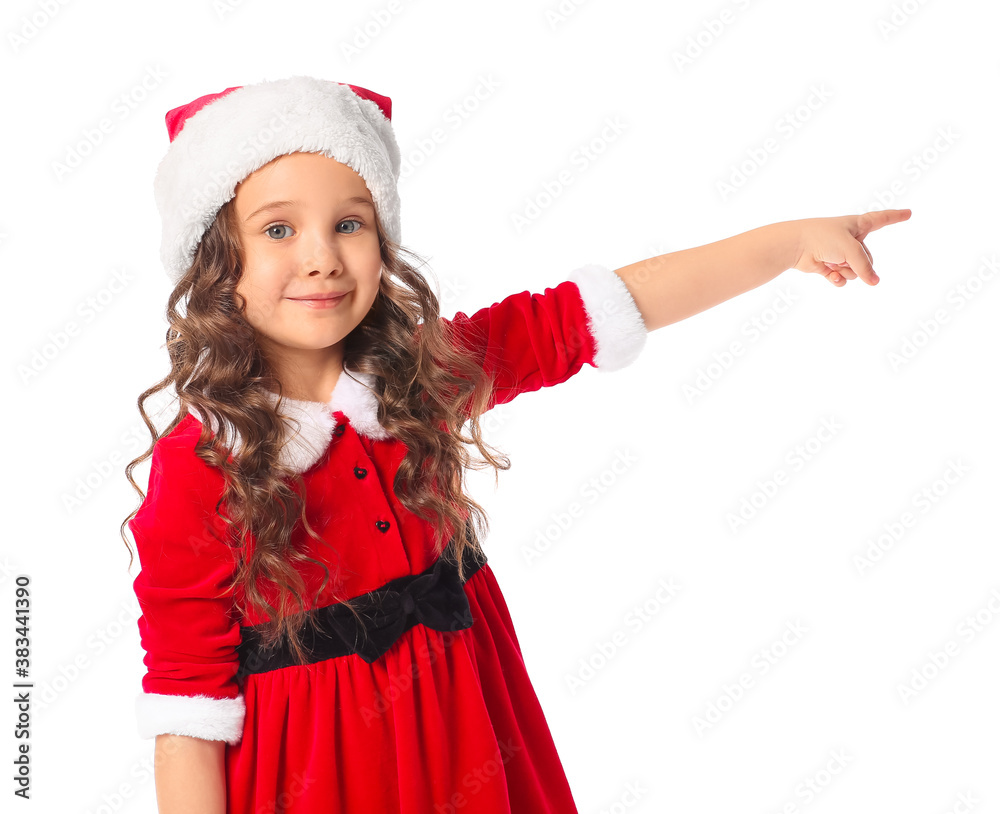 Cute little girl in Santa costume pointing at something on white background