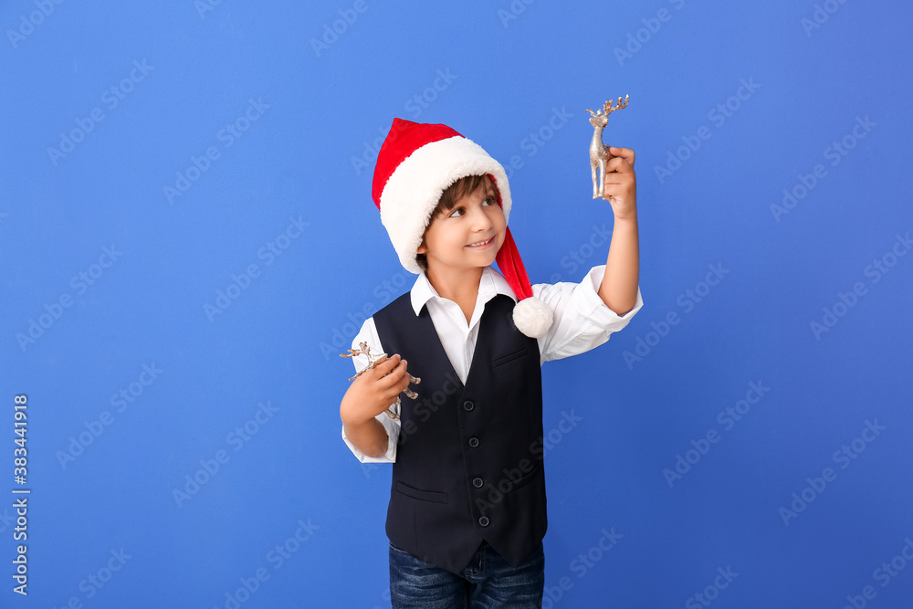 Cute little boy in Santa hat on color background